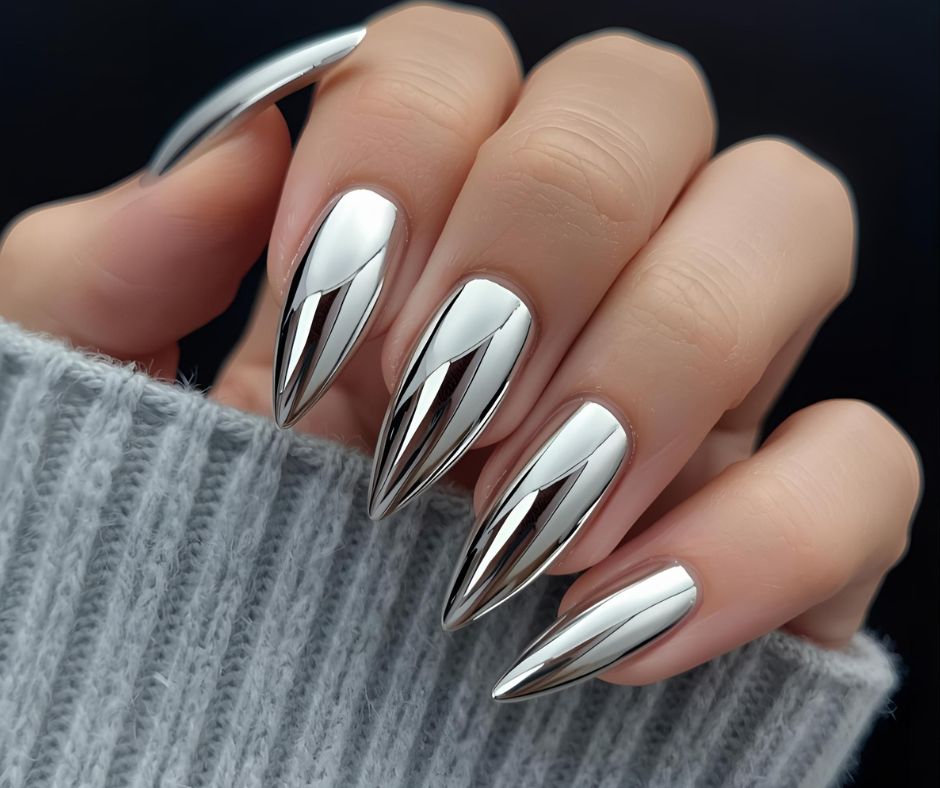 Hand with metallic nail design holding a phone, wearing a gray sleeve.