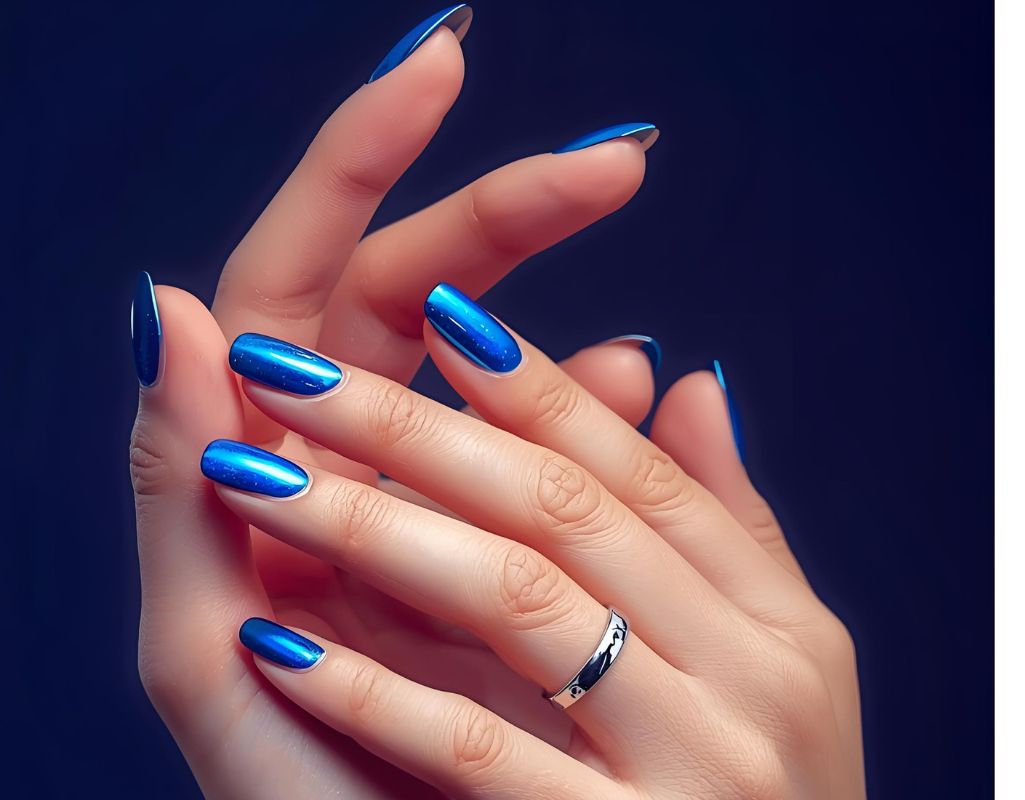 Close-up of hands with blue chrome nail polish on a dark background